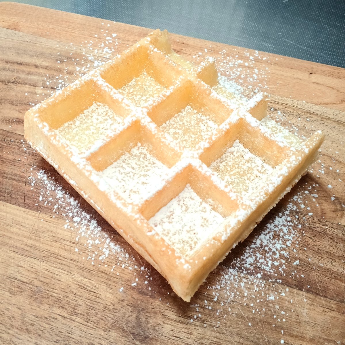 木のボードにのせた粉砂糖のブリュッセルワッフル